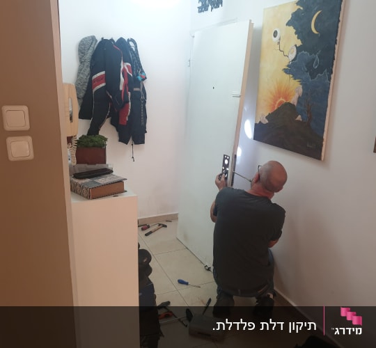אדם מתקין מנעול בדלת עם כלים